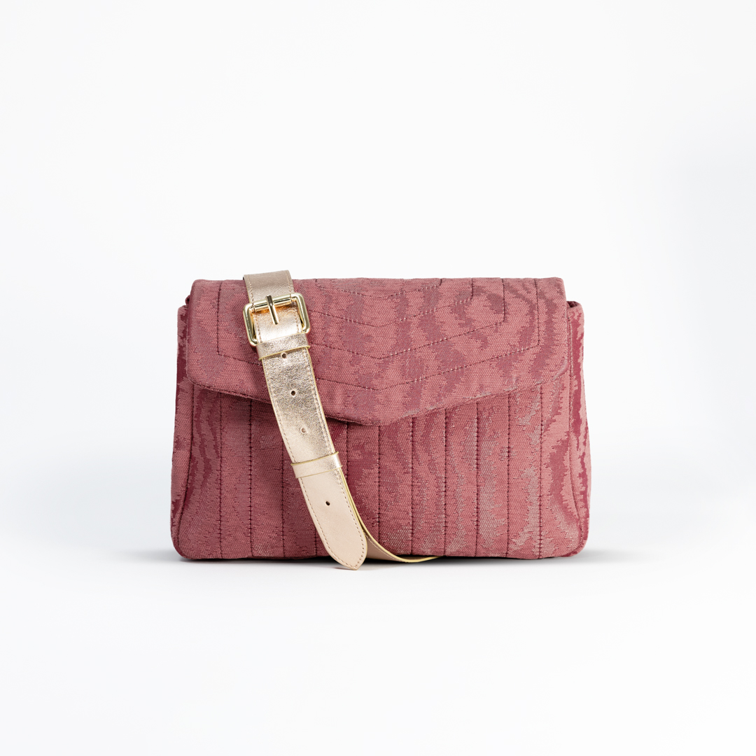 Close-up of the Ballet Blush crossbody bag in pink moiré jacquard with a golden leather strap.