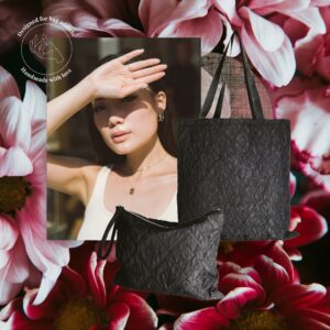 Black textured tote bag and matching pouch displayed as a set against a floral background, with a lifestyle portrait image layered behind. The structured fabric surface and long handles are visible.