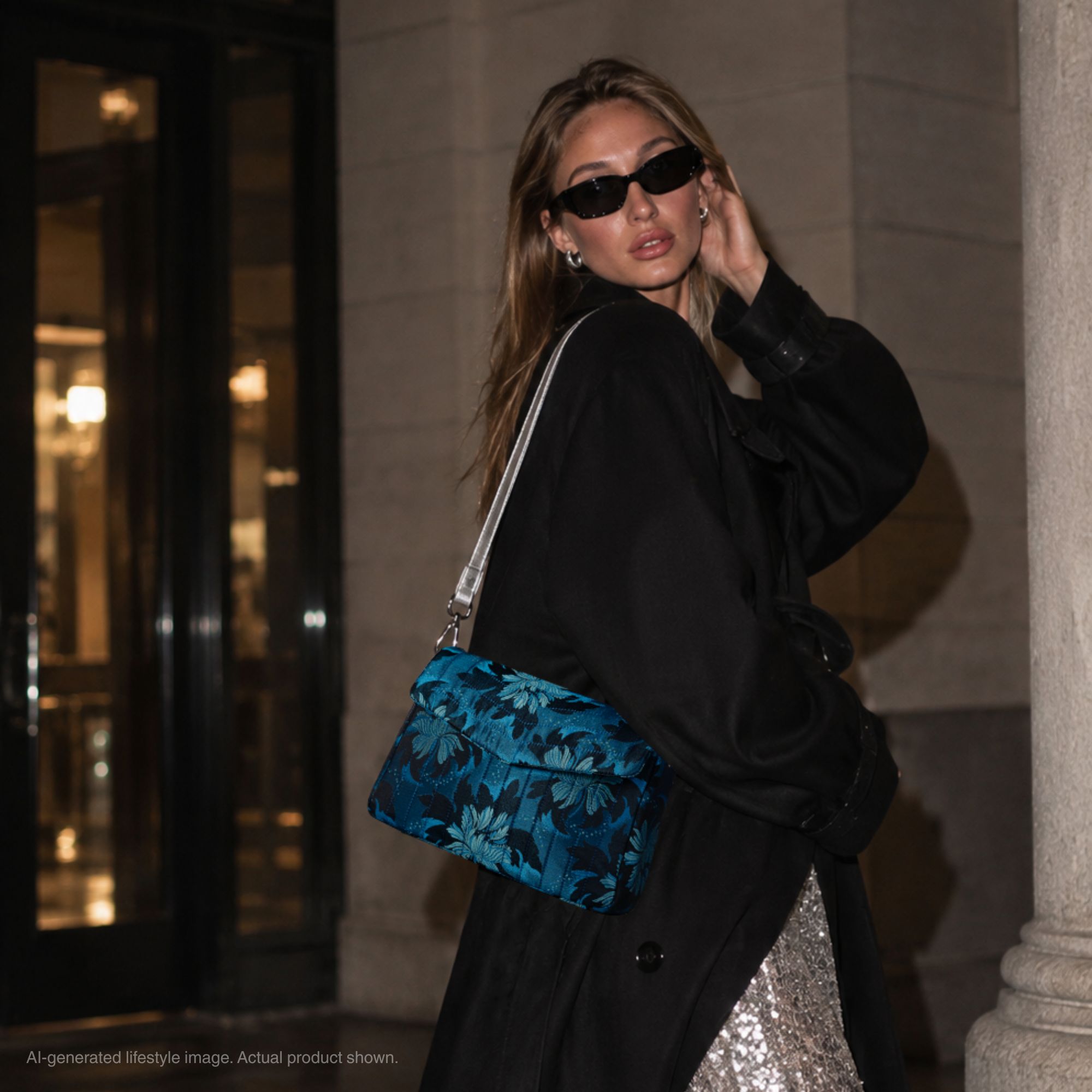 Model wearing the Gemstone Garden blue floral jacquard crossbody bag with a silver leather strap and black outfit.